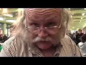 Barry Pateman, a white man bald on top with long, grey hair down the sides and a white mustache, looking over his glasses
